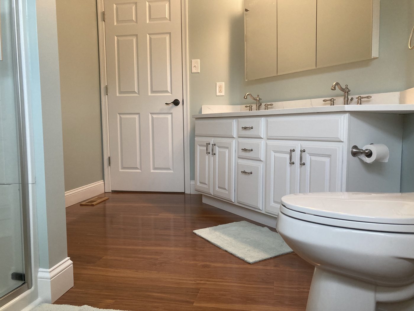 Finished bathroom with double vanity and wood-look floor